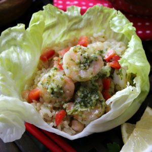 Pesto Shrimp Salad Wraps topped with red peppers and served on a wooden platter.