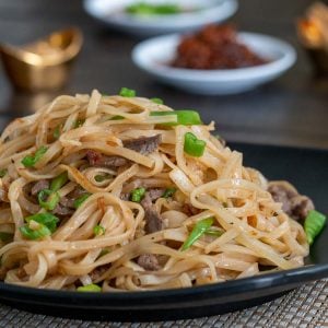 Huge bowl of Beef Noodles with Spicy XO sauce on a black plate.