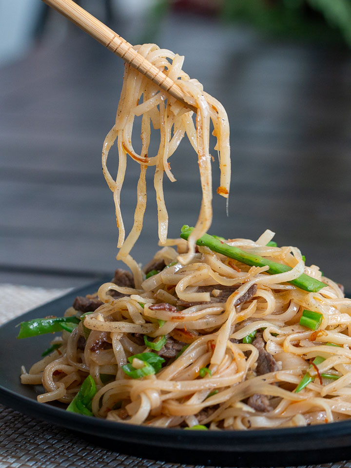 A spoonful of pan fried noodles picked up with chopsticks. Ready to eat.