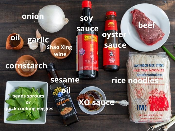 All ingredients to make Beef Noodles and spicy XO sauce laid out on a dark wooden board.