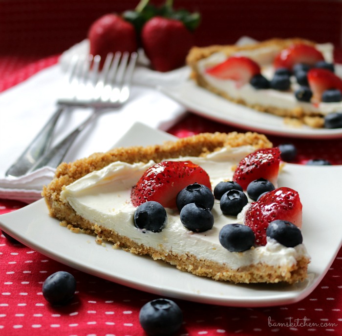 Mouthwatering slice of cheesecake bars with strawberries in the background.