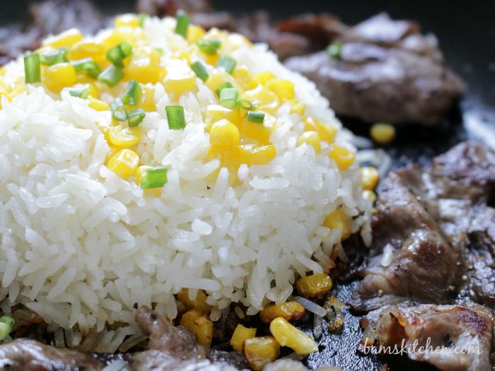 Close up of the rice showing the crispy bottom and the corn and scallions on top next to the beef. 