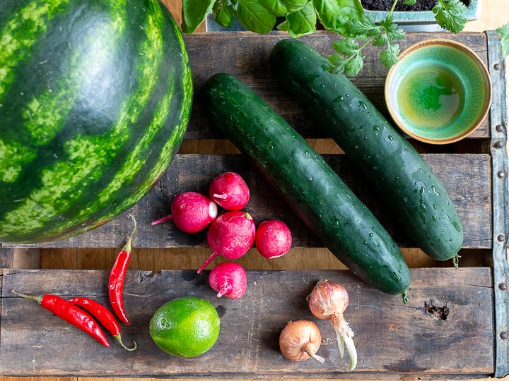 Ingredients to make salad on a wooden plank board.