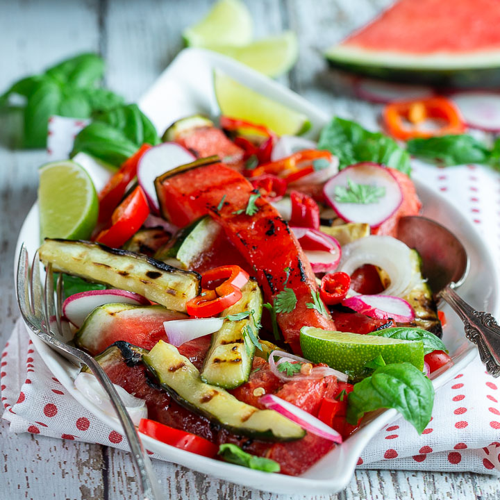 Thai Style Grilled watermelon salad on a white plate with a polka dot napkin.