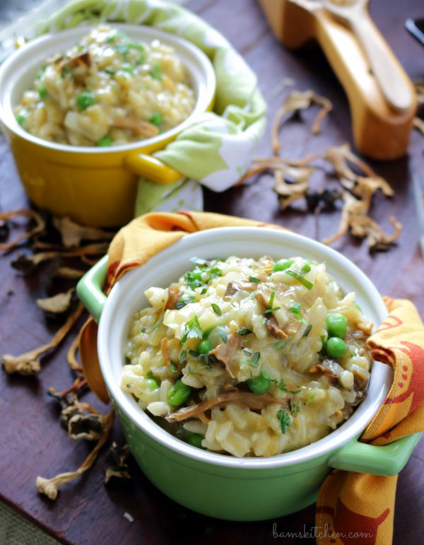 2 bowls of mushroom risotto on a wooden board with a grating of parmesan cheese.