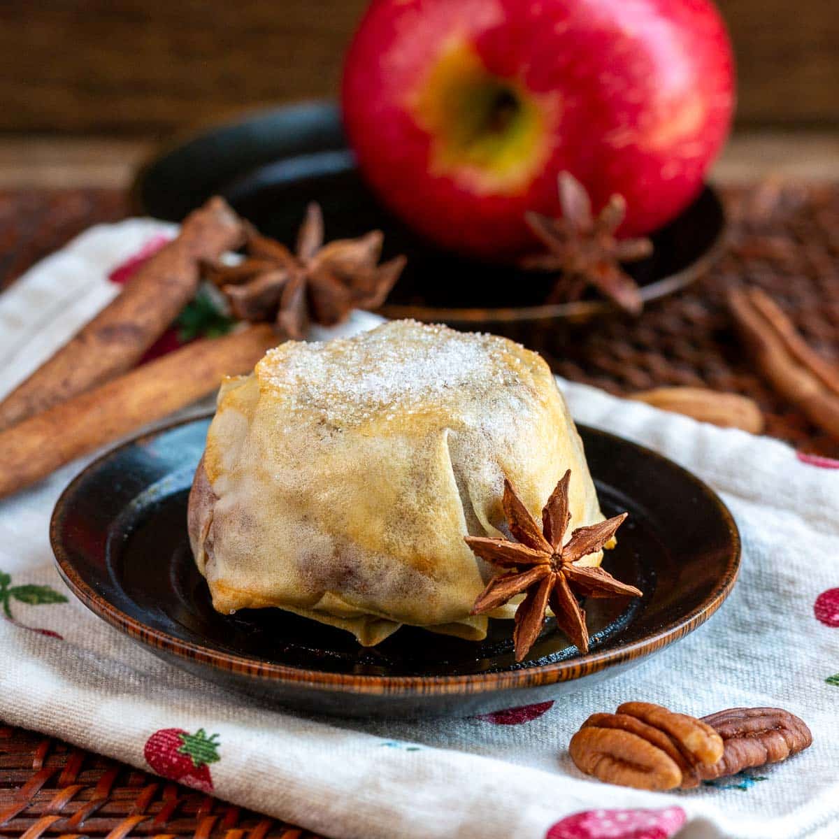 Whole apple mooncake on a black wooden bowl with a star anise and cinnamon twills on the side as a garnish. 