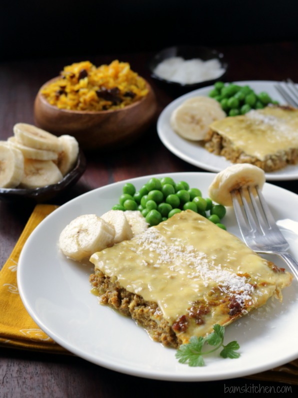 Showing Bobotie served with a side of bananas, yellow rice and desiccated coconut.  