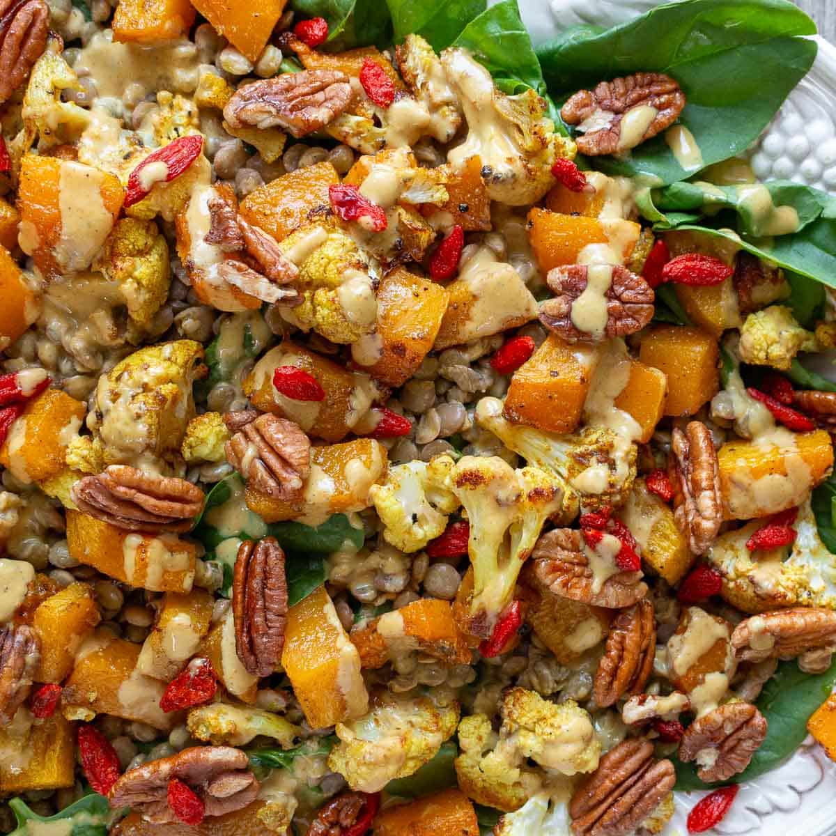 Close up of the roasted butternut squash and cauliflower all golden and colorful over the greens. 