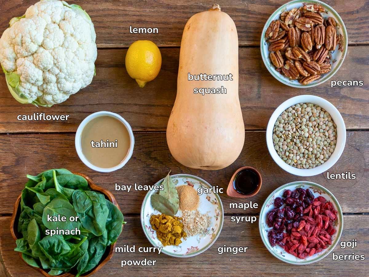 Ingredients to make a salad with roasted vegetables laid out on a wooden table.