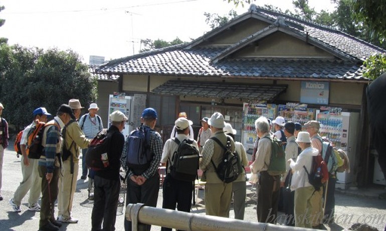 Group of Japanese males maybe in their 50-70's all wearing beige fishing vest and backpacks. 