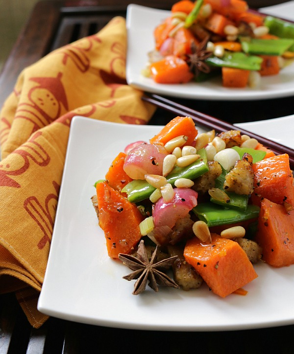 2 plates of delicious stir fried sweet potatoes and veggies topped with toasted pine nuts.