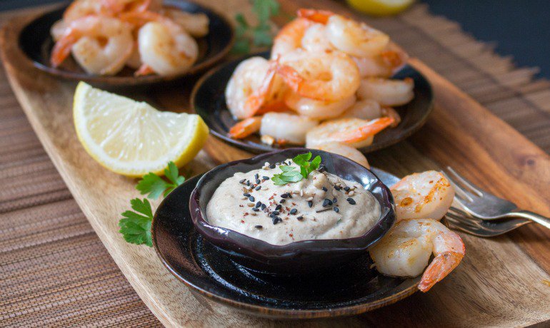 2 plates of Piled high shrimp plates with a little tahini sauce in front.