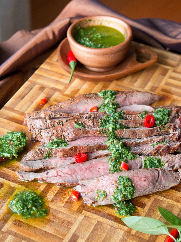 Medium rare flank steaks with sauce and chili peppers.
