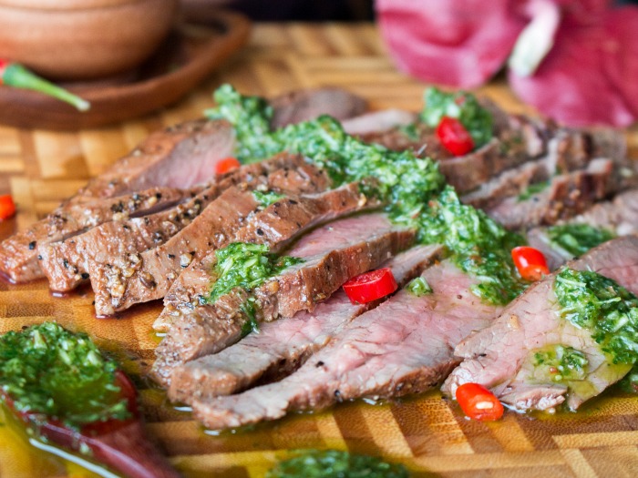 Grilled Flanks Steaks with Thai Style Chimichurri on a wooden cutting board.