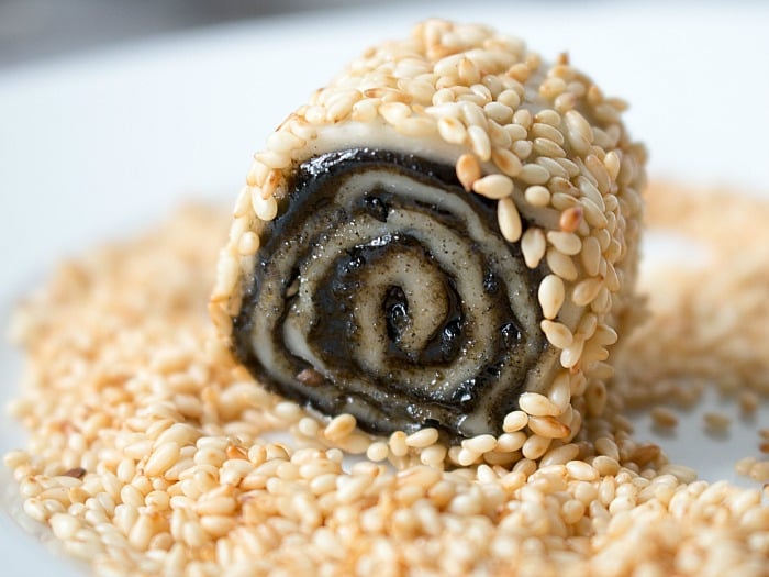 Cookie getting rolled in the sesame seeds ready to be baked.