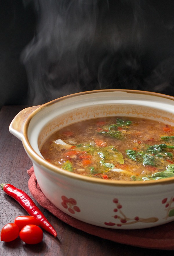 Big Chinese soup bowl filled steaming broth rising. 