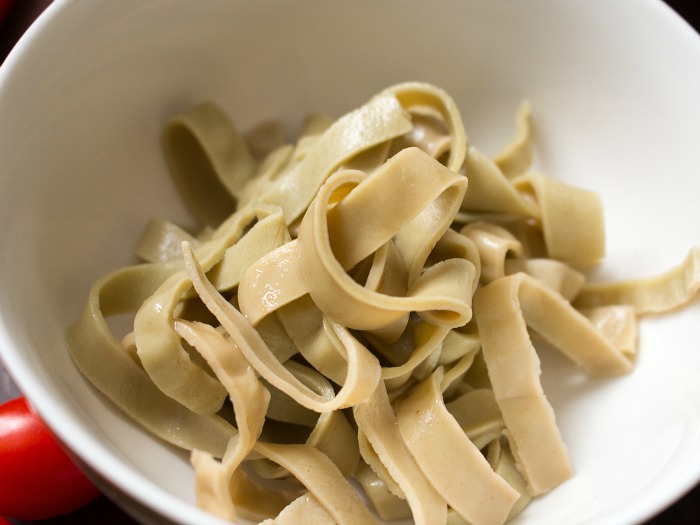 Cooked edamame mung bean noodles in a white bowl. They are slightly green in color. 