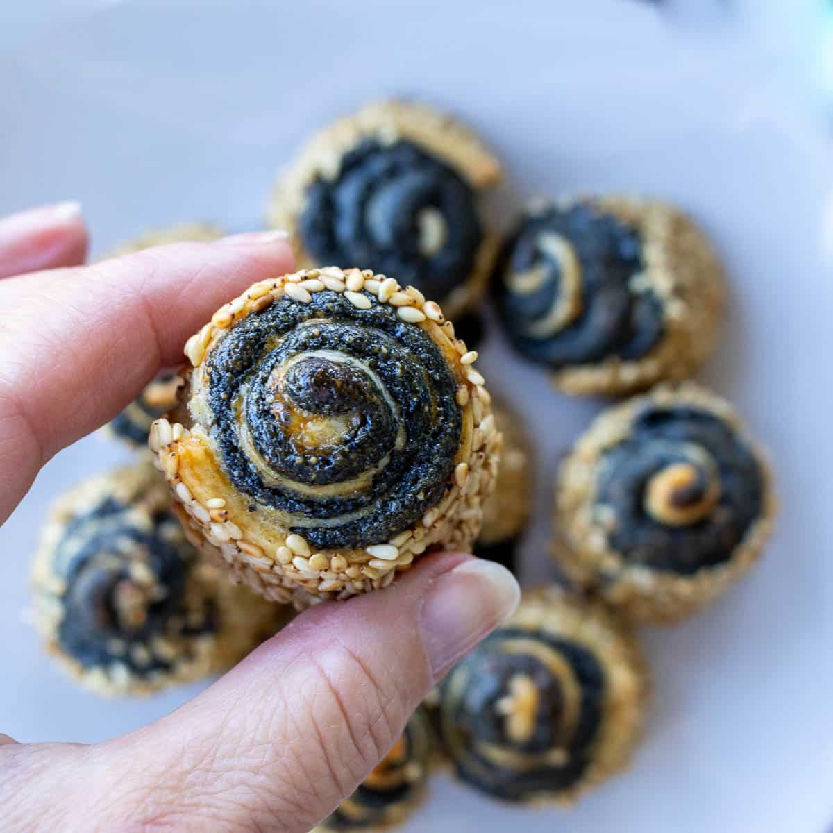 Holding on to a black sesame pinwheel cookies showing the crispy texture on the outside.