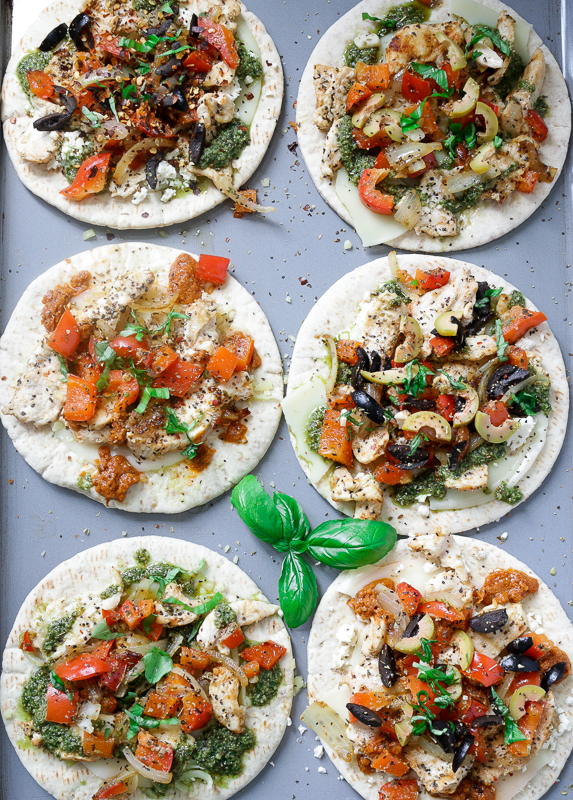 pita pizzas with all different toppings ready to get baked.