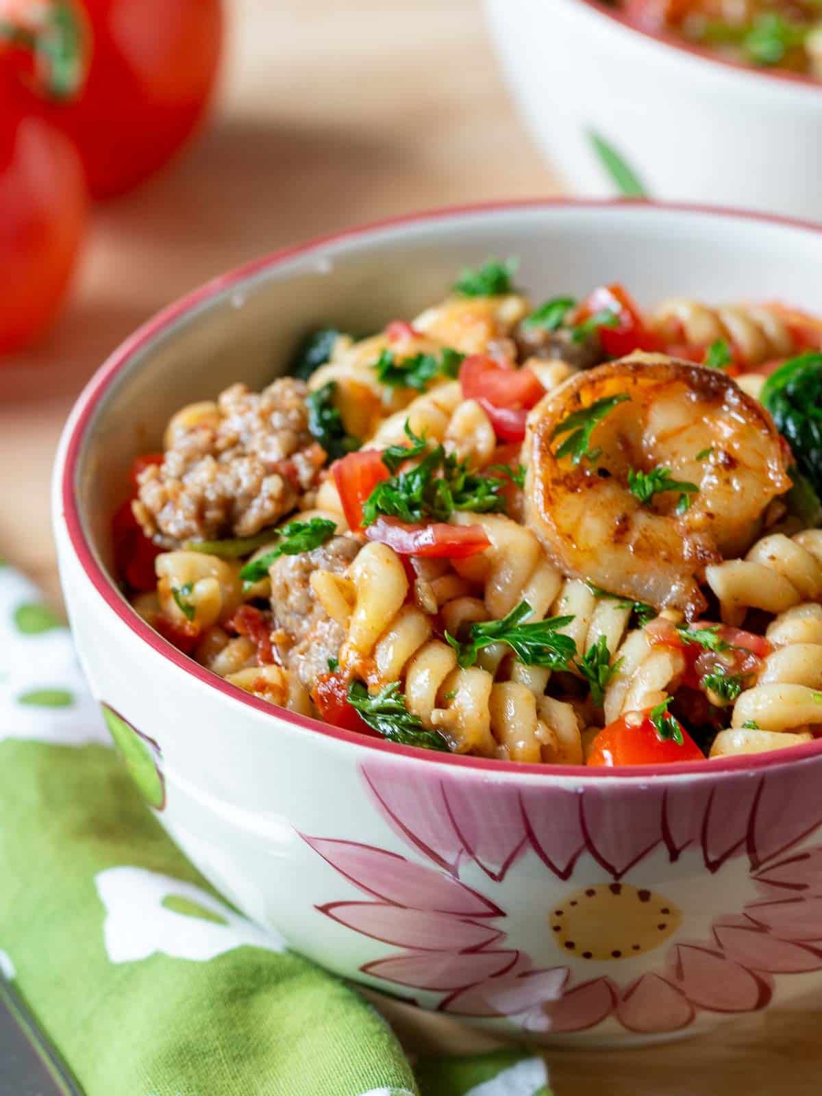 Italian sausage and shrimp mixed with a saucy pasta and served in a flowered bowl.