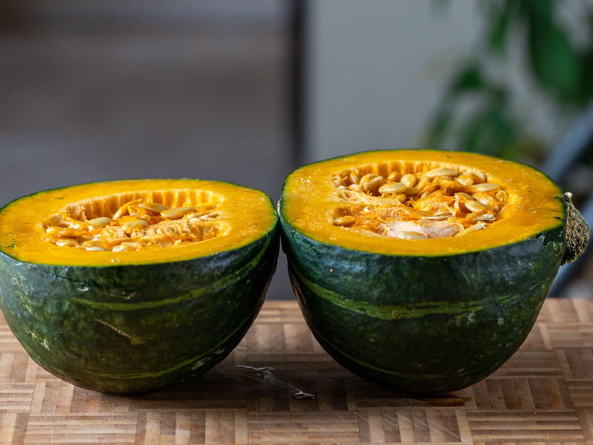 Kabocha squash cut in half on a cutting board.