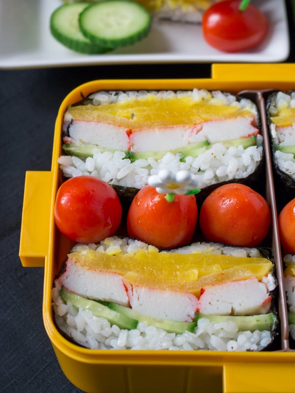 Close up showing the layers of crab, rice, Japanese pickles in the sushi hand held sandwich. 