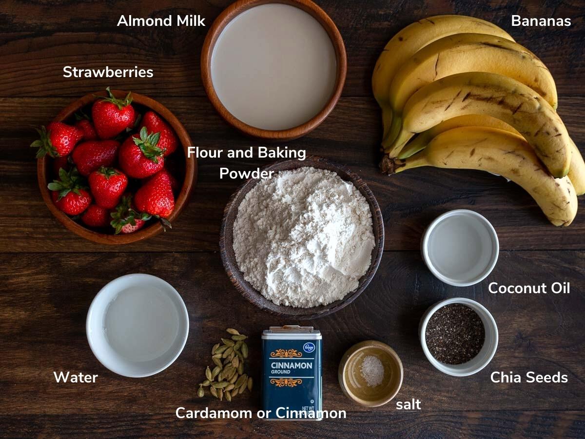 Ingredients to make strawberry chia seed pancakes laid out on a wooden board. 