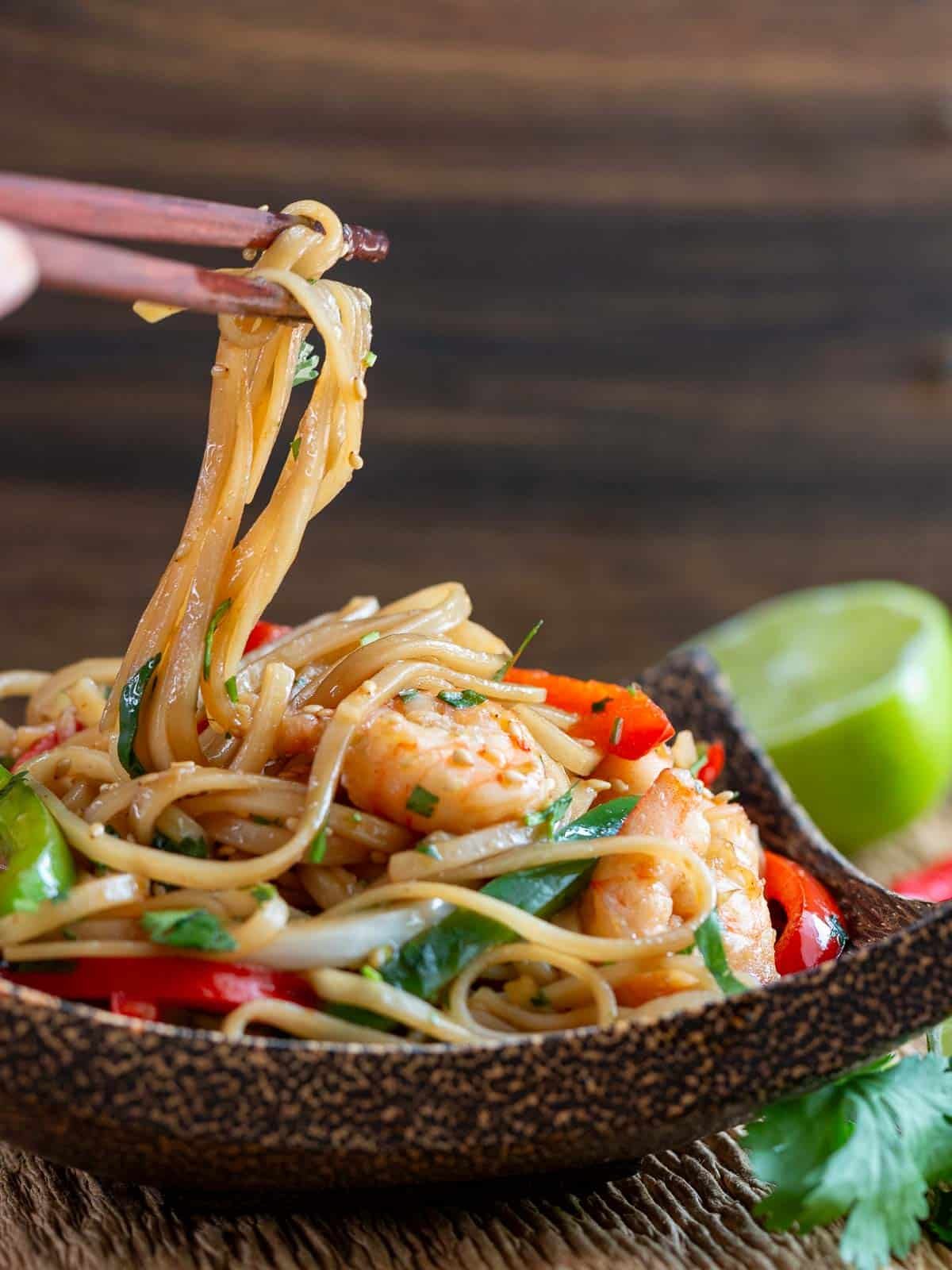 Chili lime cilantro noodles getting picked up with chop sticks. 