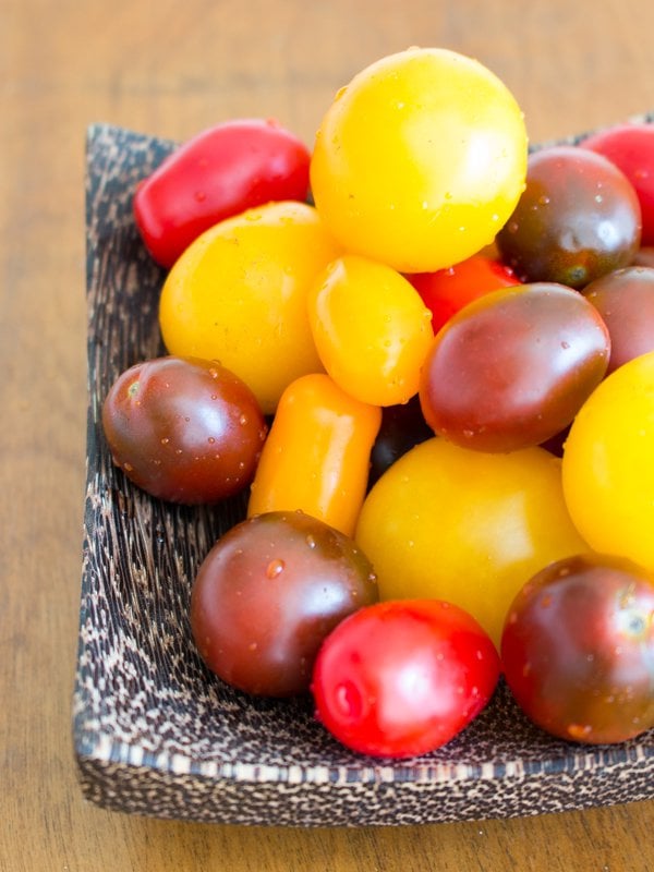 Bowl of fresh mixed cherry heirloom tomatoes. Some are yellow, red and this green and red mix. 