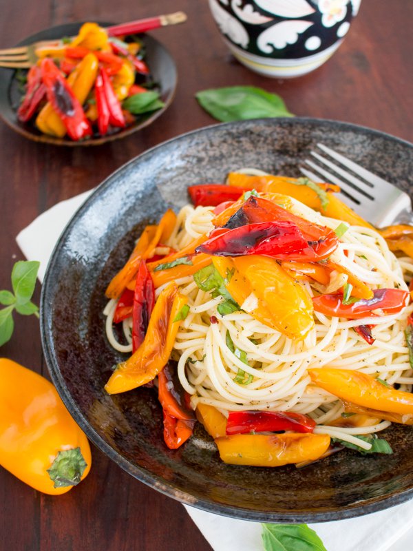 Roasted Yellow and red peppers with tasseled pasta with roasted peppers and an olive oil dispenser in the background.