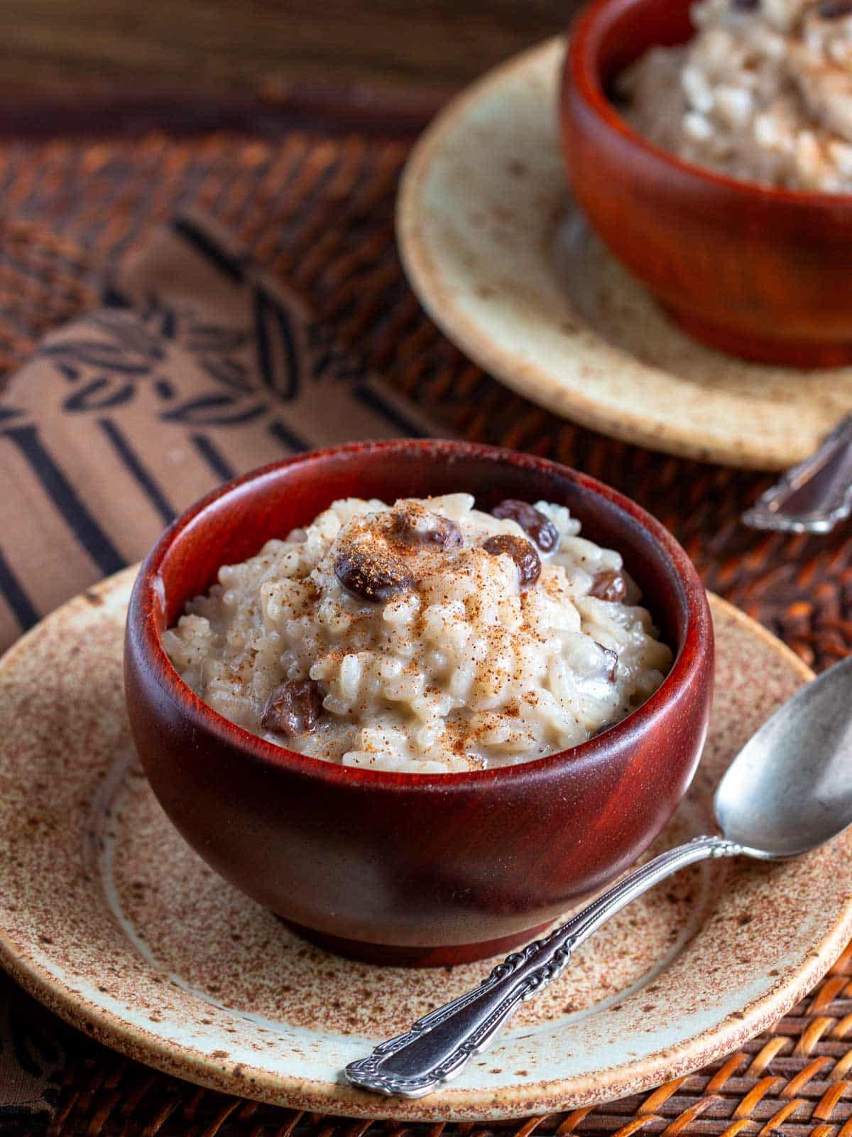 2 vegan rice puddings in wooden bowls on a wooden table. 