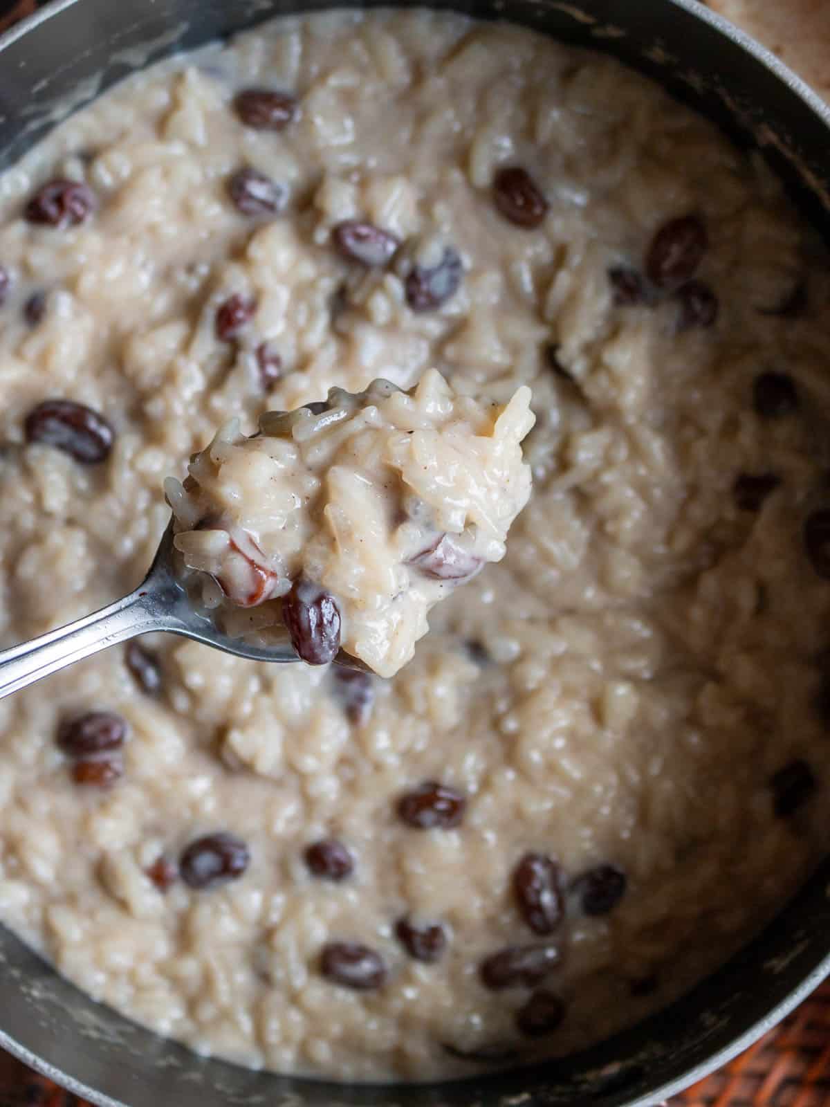 Gluten free rice pudding in saucepan showing a creamy spoonful. 