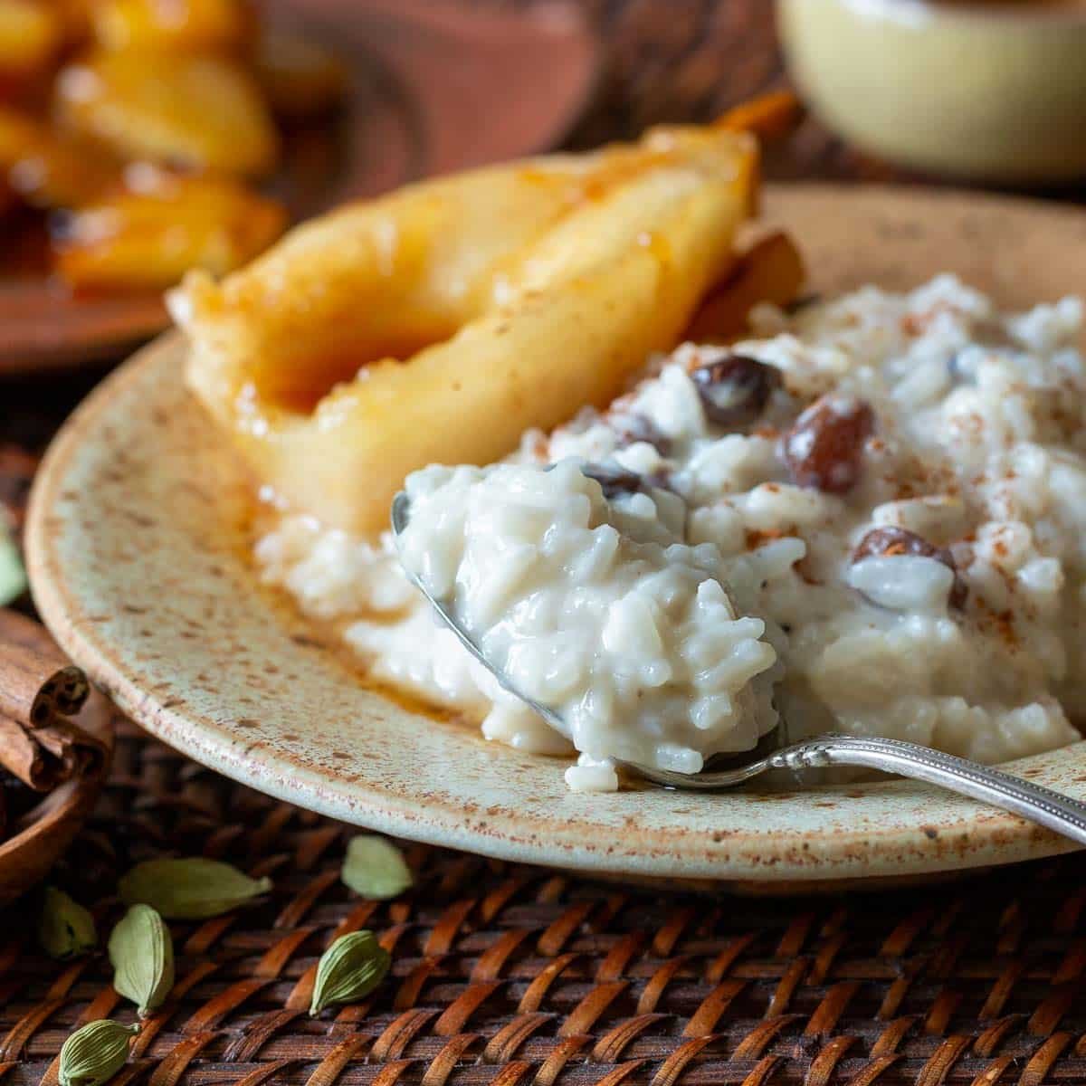 Spoonful of creamy coconut rice pudding in a luxurious large beige bowl with poached pears.