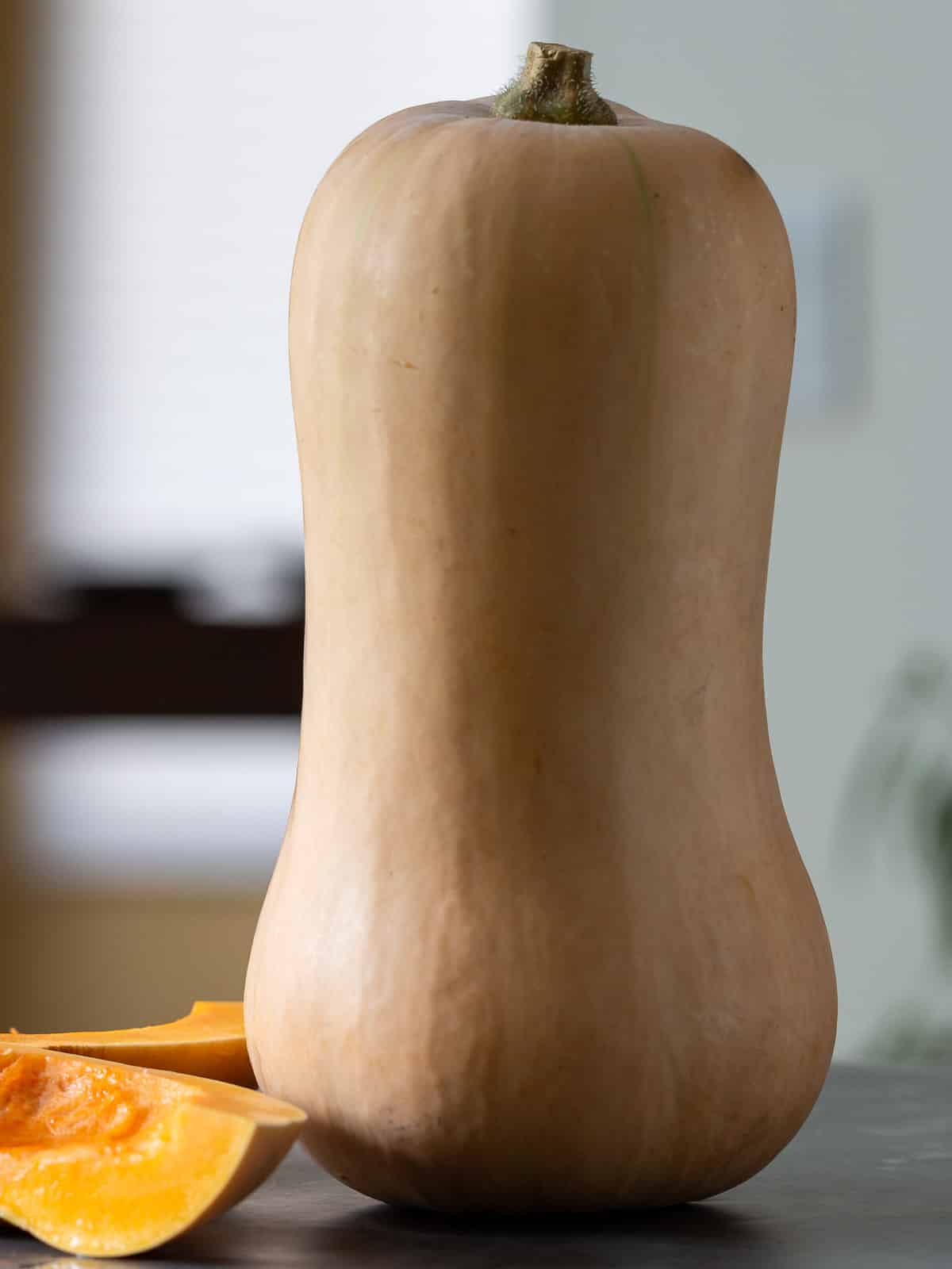 A whole uncooked butternut squash sitting upright on a table.