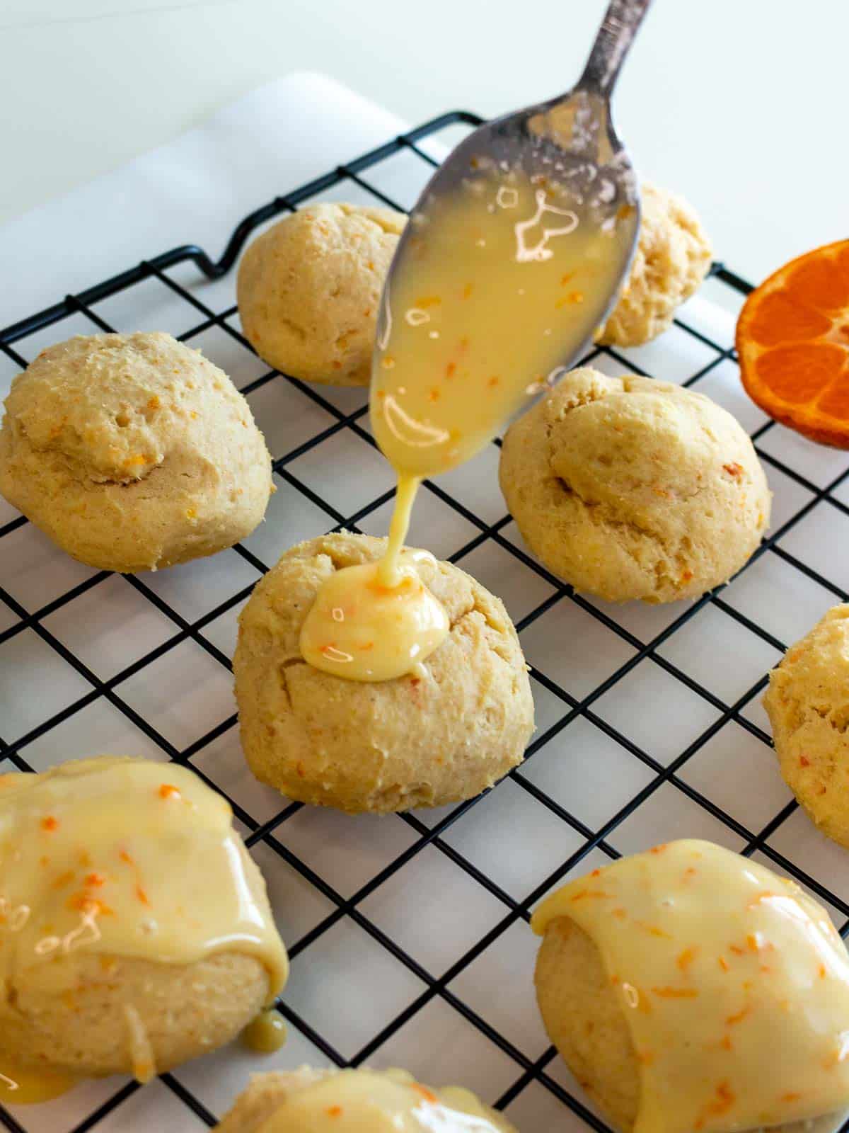 Drizzling on the orange icing on the Italian orange cookies that are on a cooling rack. 