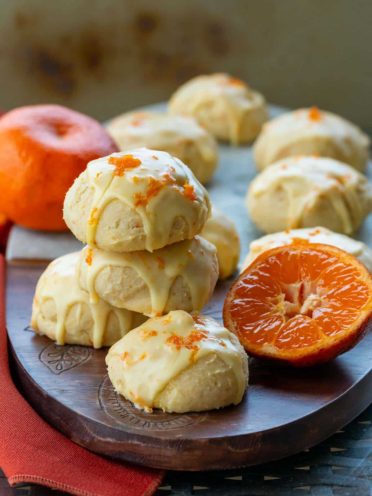 Italian orange drop cookies on a wooden board that have been glazed and garnished with orange zest. 