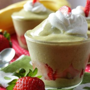 Matcha nice cream topped with coconut whipped cream and strawberries.