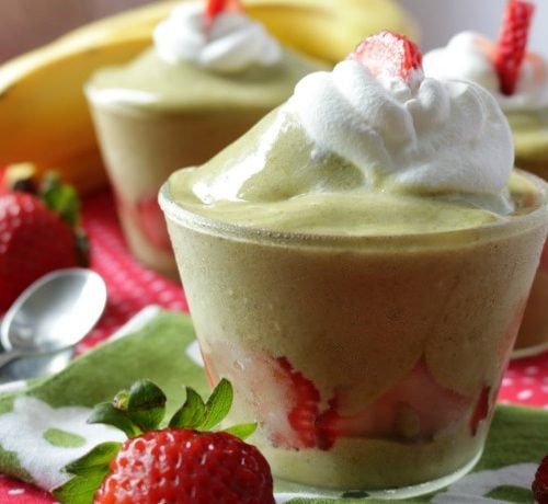Matcha nice cream topped with coconut whipped cream and strawberries.