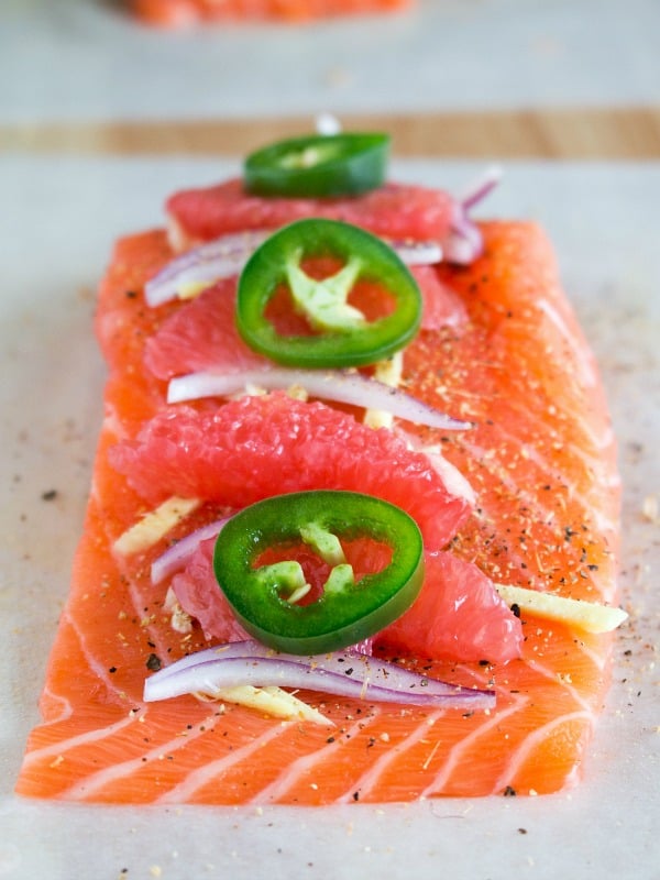 Salmon laid our on parchment paper getting filled with all the fresh ingredients. 