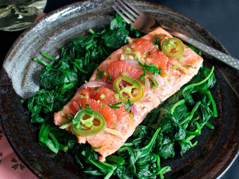 Spicy Citrus Baked Salmon on a black plate ready to eat.