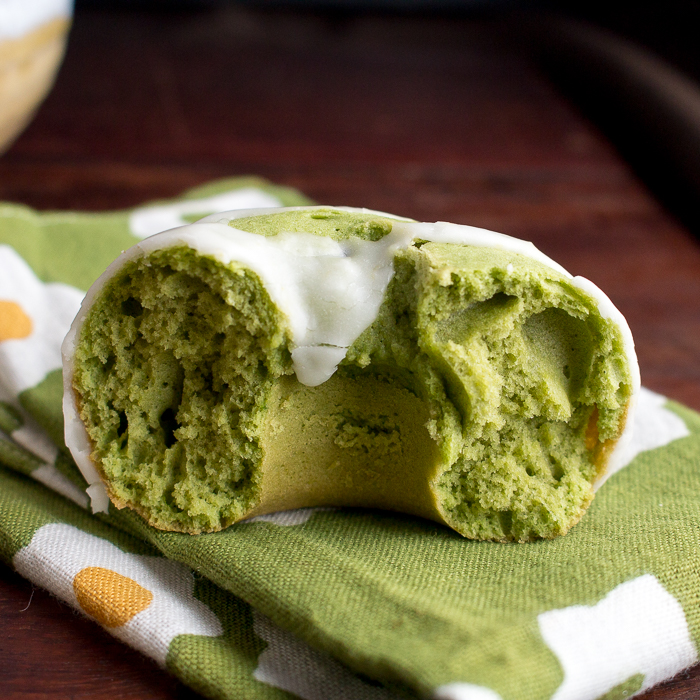 A bite out of a matcha donut laying on a green towel.