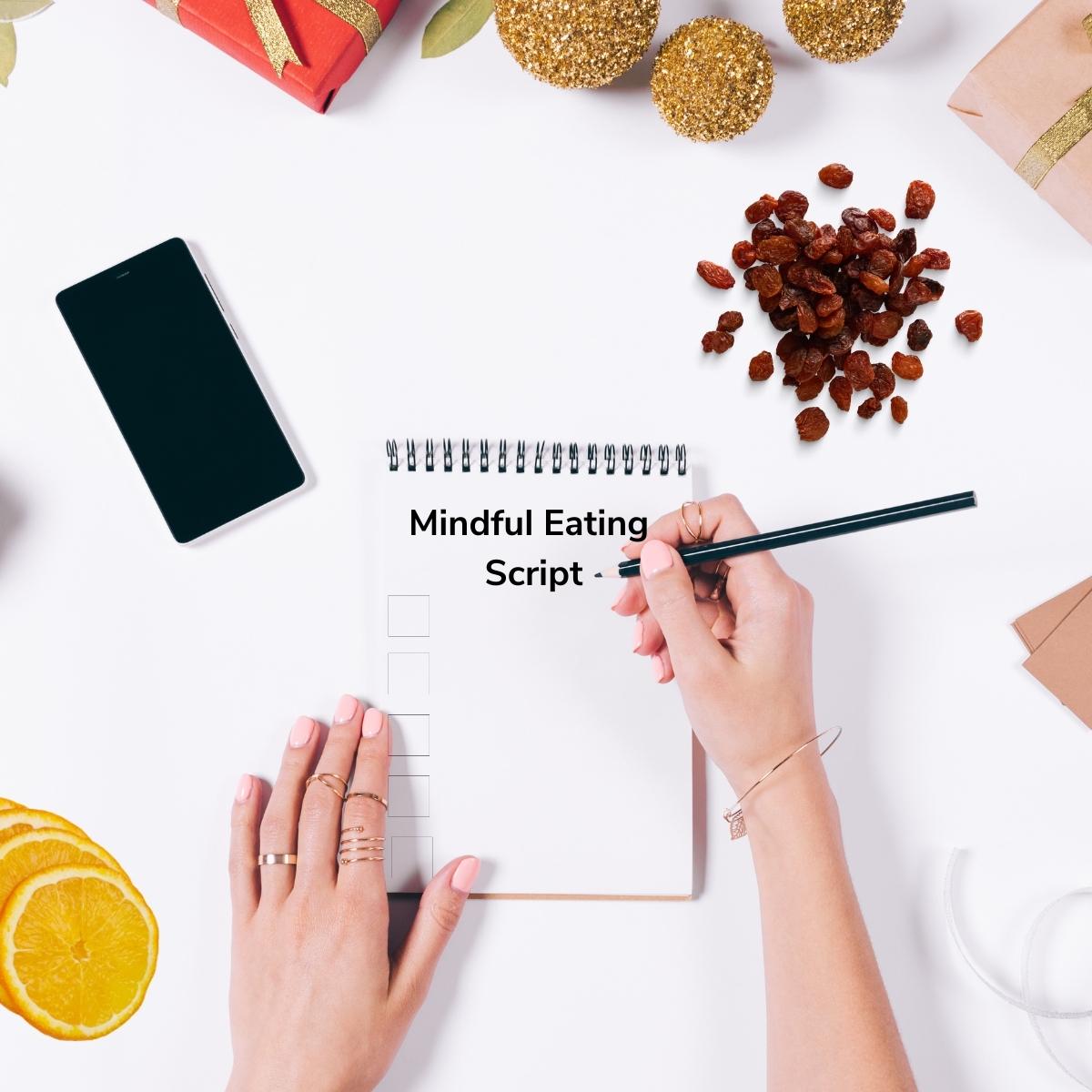 A person writing out a mindful eating script with raisins and oranges on the table.