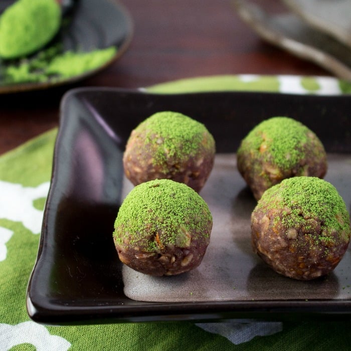 Matcha Red Bean Energy Balls all lined up in a row and the dusting of super bright green antioxidant rich green tea on top. 