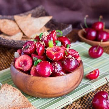 Fresh cherry salsa made with ginger in a wooden bowl served with homemade tortillas.