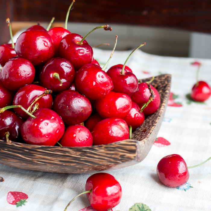 Bright red Cherries in a wooden bowl.