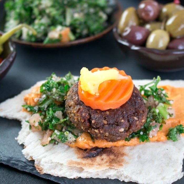 Flat bread topped with red pepper hummus, Tabbouli, falafel and pickled vegetables.