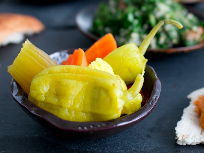 A bowl of pickled vegetables like carrots, peppers, etc in a little mini brown bowl. 