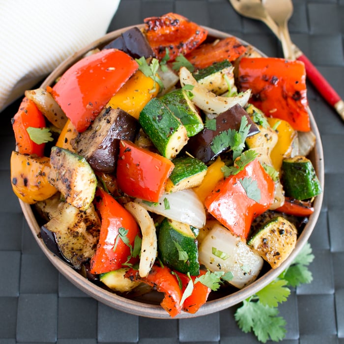 Provencal Ratatouille in a beige bowl with red handled utensils.
