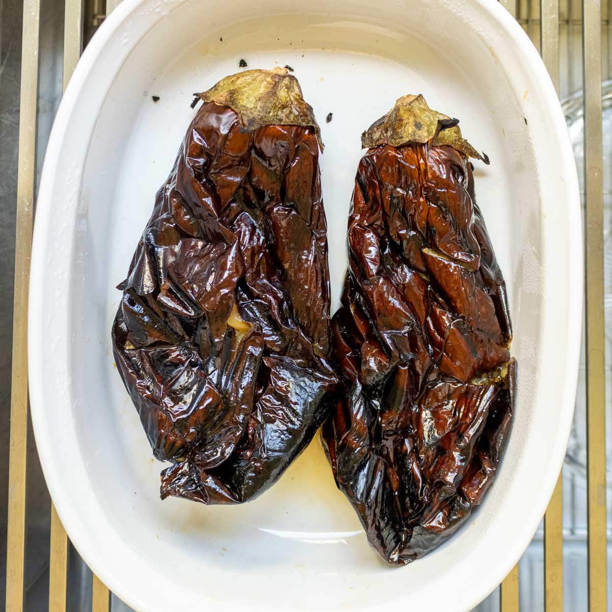 fire roasted chargrilled eggplants transferred to a white bowl.
