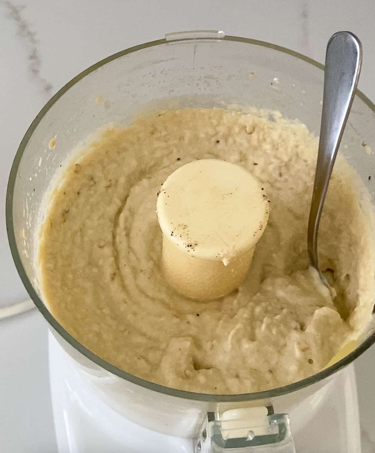Shot of prepared grilled eggplant, tahini, garlic, lemon juice, salt and EVOO blended to a creamy smooth texture in the food processor.